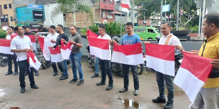 Personil Polresta Ambon membagikan bendera merah putih sambut HUT Kemerdekaan RI ke 80.